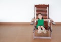 Happy little Asian child girl relaxing on Thai wooden traditional chair Royalty Free Stock Photo