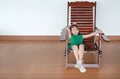 Happy little Asian child girl relaxing on Thai wooden traditional chair Royalty Free Stock Photo