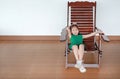 Happy little Asian child girl relaxing on Thai wooden traditional chair