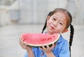 Happy little Asian child girl in school uniform enjoy eating watermelon outdoors Royalty Free Stock Photo
