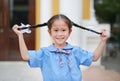 Happy little Asian child girl in school uniform holding her two tied ponytails hairs Royalty Free Stock Photo