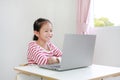 Happy little Asian child girl sitting at desk and using laptop computer Royalty Free Stock Photo
