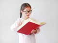 Happy little Asian child girl wearing eyeglasses and hold a book and write with pencil on white background Royalty Free Stock Photo