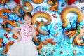 Happy little Asian child girl wearing pink Traditional cheongsam dress for Chinese New Year celebration on chinese dragon wall