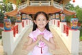 Happy little Asian child girl wearing pink traditional cheongsam dress with greeting gesture celebration for Chinese New Year on Royalty Free Stock Photo