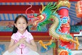 Happy little Asian child girl wearing pink traditional cheongsam dress with greeting gesture celebration for Chinese New Year on Royalty Free Stock Photo