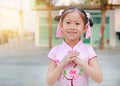 Happy little Asian child girl wearing pink traditional Chinese dress with greeting gesture celebration for Chinese New Year