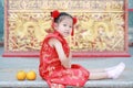 Happy little Asian child girl wearing red cheongsam with greeting gesture celebration for Chinese New Year at chinese temple in Royalty Free Stock Photo