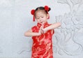 Happy little Asian child girl wearing red cheongsam with greeting gesture celebration for Chinese New Year at chinese temple in Royalty Free Stock Photo