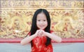 Happy little Asian child girl wearing red cheongsam with greeting gesture celebration for Chinese New Year at chinese temple in Royalty Free Stock Photo