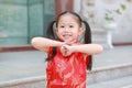 Happy little Asian child girl wearing red cheongsam with greeting gesture celebration for Chinese New Year at chinese temple in Royalty Free Stock Photo