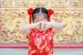 Happy little Asian child girl wearing red cheongsam with greeting gesture celebration for Chinese New Year at chinese temple in Royalty Free Stock Photo