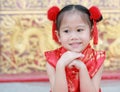 Happy little Asian child girl wearing red cheongsam with greeting gesture celebration for Chinese New Year at chinese temple in Royalty Free Stock Photo