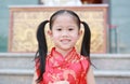 Happy little Asian girl in Cheongsam respecting on traditional Chinese new year festival on Chinese background