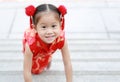 Happy little Asian girl in Cheongsam respecting on traditional Chinese new year festival on Chinese background