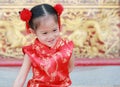 Happy little Asian girl in Cheongsam respecting on traditional Chinese new year festival on Chinese background