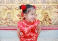 Happy little Asian girl in Cheongsam respecting on traditional Chinese new year festival on Chinese background