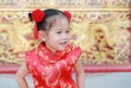 Happy little Asian girl in Cheongsam respecting on traditional Chinese new year festival on Chinese background