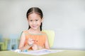 Happy little Asian girl drawing and painting with water color on paper in children room with looking at camera Royalty Free Stock Photo