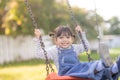 Happy little Asian girl playing swing outdoor in the park