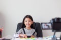 Happy little Asian girl sitting at the white table and live streaming for social media with happiness by camera select focus