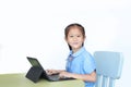 Happy little Asian girl using Laptop computer to do homework on desk over white background Royalty Free Stock Photo