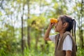 Happy Little Asian girls looking ahead and smiling child with the binoculars in the park. Travel and adventure concept. Freedom, Royalty Free Stock Photo