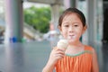 Happy little Asian kid girl enjoy eating ice cream cone with stained around her mouth Royalty Free Stock Photo