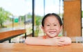 Happy little Asian kid girl lying on the wood table bar with looking camera. Royalty Free Stock Photo