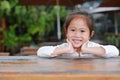 Happy little Asian kid girl lying on the wooden table with looking camera Royalty Free Stock Photo