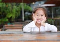 Happy little Asian kid girl lying on the wooden table with looking camera Royalty Free Stock Photo