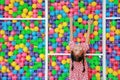 Happy little Asian kid girl playing climb and hanging on cage of playground colorful toy ball with looking camera