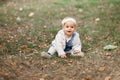 Happy little baby boy sitting on the grass in the park, garden, meadow. Baby looks at parents, beautiful warm weather Royalty Free Stock Photo