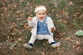 Happy little baby boy sitting on the grass in the park, garden, meadow. Baby looks at parents, beautiful warm weather Royalty Free Stock Photo