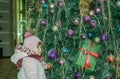 Happy little baby girl is beautiful in a white fur coat, hat, scarf near a Christmas tree decorated with toys and garlands and smi Royalty Free Stock Photo