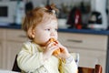 Happy little baby girl eating fresh croissant for breakfast or lunch. Healthy eating for children. Toddler child in Royalty Free Stock Photo