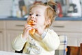 Happy little baby girl eating fresh croissant for breakfast or lunch. Healthy eating for children. Toddler child in Royalty Free Stock Photo