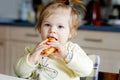 Happy little baby girl eating fresh croissant for breakfast or lunch. Healthy eating for children. Toddler child in Royalty Free Stock Photo