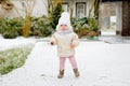 Happy little baby girl making first steps outdoors in winter through snow. Cute toddler learning walking. Child having Royalty Free Stock Photo