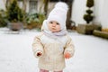 Happy little baby girl making first steps outdoors in winter through snow. Cute toddler learning walking. Child having Royalty Free Stock Photo