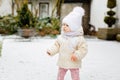 Happy little baby girl making first steps outdoors in winter through snow. Cute toddler learning walking. Child having Royalty Free Stock Photo