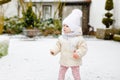 Happy little baby girl making first steps outdoors in winter through snow. Cute toddler learning walking. Child having Royalty Free Stock Photo