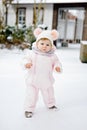 Happy little baby girl making first steps outdoors in winter through snow. Cute toddler learning walking. Child having Royalty Free Stock Photo