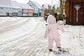 Happy little baby girl making first steps outdoors in winter through snow. Cute toddler learning walking. Child having Royalty Free Stock Photo