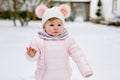 Happy little baby girl making first steps outdoors in winter through snow. Cute toddler learning walking. Child having Royalty Free Stock Photo