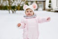 Happy little baby girl making first steps outdoors in winter through snow. Cute toddler learning walking. Child having Royalty Free Stock Photo