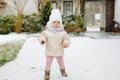 Happy little baby girl making first steps outdoors in winter through snow. Cute toddler learning walking. Child having Royalty Free Stock Photo