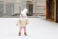 Happy little baby girl making first steps outdoors in winter through snow. Cute toddler learning walking. Child having Royalty Free Stock Photo