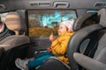 Happy little baby girl sitting in a child seat in the back seat of a car. The concept of safe automobile trip and child Royalty Free Stock Photo