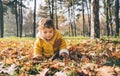 Happy little baby girl in yellow jacket outdoor crawling and playing with autumn leaves. Child having fun in fall season. Smiling Royalty Free Stock Photo